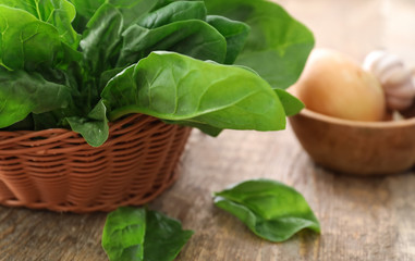 Wicker basket with fresh spinach leaves on table
