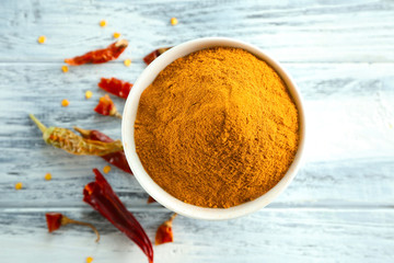 Chili powder and dried pepper pods on wooden table, top view