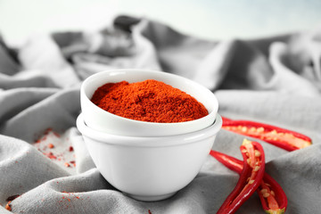 Red chili powder and cut pepper pods on grey fabric