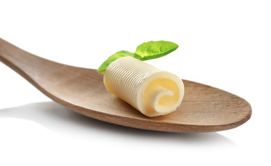 Wooden spoon with delicious butter curl and basil on white background