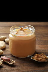 Jar with creamy peanut butter on table