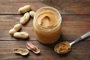 Jar with creamy peanut butter on table