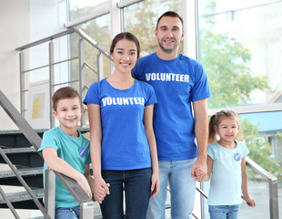 Happy volunteers and children standing on stairs indoors