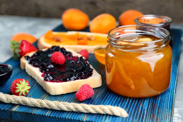 Jar and bread with jam on wooden tray