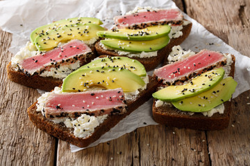 Delicious sandwiches with fried tuna, sesame, avocado and cottage cheese close-up. horizontal