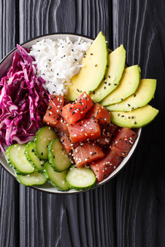 Hawaiian tuna poke bowl with avocado, red cabbage, cucumber and sesame seeds. Vertical top view