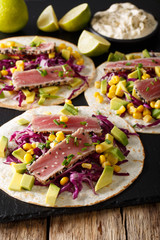 tortilla with tuna steak, sesame and fresh vegetables close-up. vertical