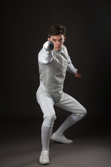 Young male fencer in white fencing costume Attacking pose - obrazy, fototapety, plakaty