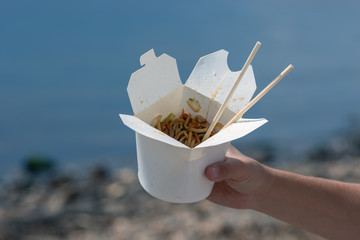 A man is eating udon noodles. Food on the beach. Street Food