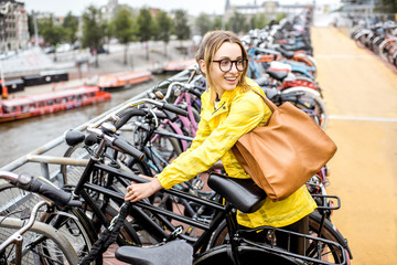 Fototapeta na wymiar Young woman tourist in yellow raincoat parking a bicycle on the multilevel parking in Amsterdam
