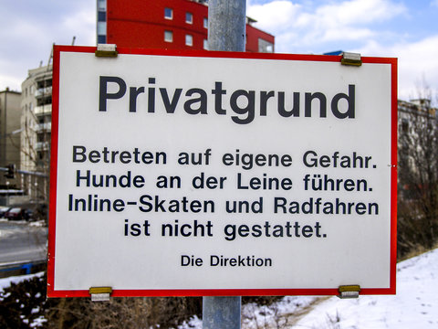 Schild Privatgrund, Betreten auf eigene Gefahr. Hunde an der Lei