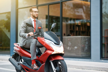 Fototapeta na wymiar Delighted modern businessman riding a motorbike