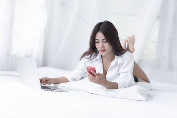 Young woman writing on a computer while in bed