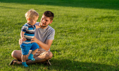 Naklejka na ściany i meble Happy father and son having fun outdoor on meadow