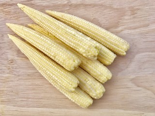 Closeup A pile of baby corns set on wooden background. Raw baby corn on wooden background. Top view with Copy space.Selective focus.