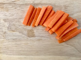Closeup A pile of fresh carrots cut into strips set on wooden board. Stripped carrots on wooden background. Top view with Copy space.Selective focus.