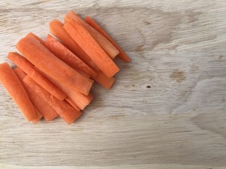 Closeup A pile of fresh carrots cut into strips set on wooden board .Uncooked stripped carrots on wooden background. Top view with Copy space.Selective focus.