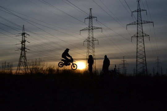 three  guys`s  silhouettes during extrim motocross training against the background of the sunset 