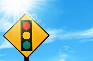 Traffic light warning sign on blue sky and sun light white clouds background.