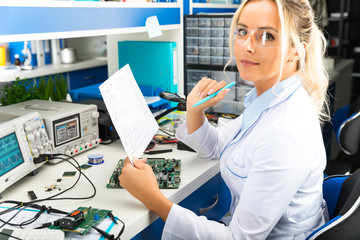 Female electronic engineer checking electronic circuit in laboratory