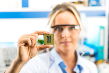Young female electronic engineer holding CPU in hand