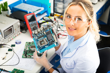 Female electronic engineer holding computer motherboard in hands in the laboratory