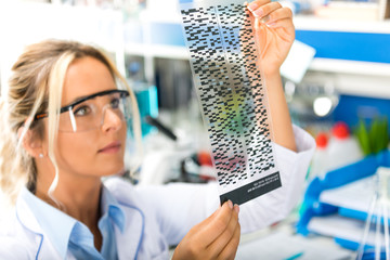 Young attractive female scientist examiming DNA autoradiogram results