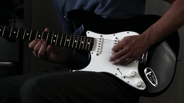 Close-up view of hands playing electric guitar