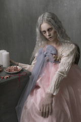 Dark halloween portrait of scary bad zombie girl sitting in a chair and collecting hearts....