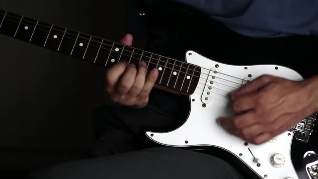 Close-up view of hands playing electric guitar