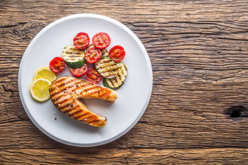 Salmon. Grilled salmon steak with tomatoes and zucchini on white plate