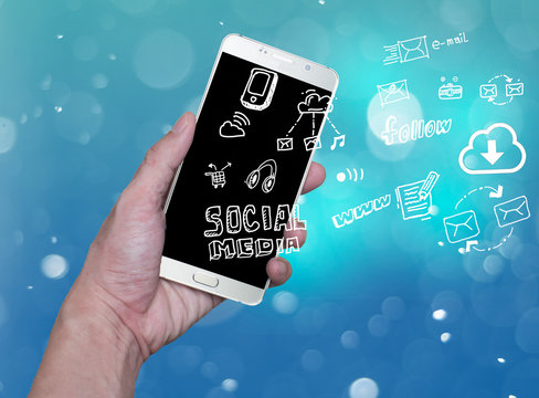 hand holding mobile phone with cloud computing with blue background .Hand holding smartphone with hand drawn media icons and symbols concept style. - Powered by Adobe