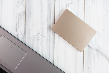 Flat lay design bronze colour external hard drive on white wooden background,top view