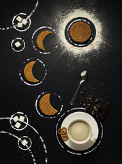 Tea time in space / Creative concept photo of tableware with pastry arranged as galaxy on black background.