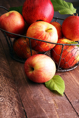Ripe red apples with leaves on wooden background