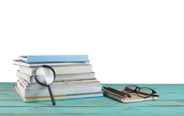 Stack of  books with magnifying glass on wooden table,white background