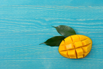 Sliced mango with leaves on a blue wooden background, top view