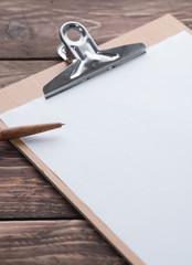 Clipboard with blank white paper and pen on wood