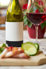 A bottle and glass of wine with food in a restaurant