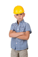 Serious cute boy in blue checkered shirt, grey jeans and yellow building helmet, isolated on white background