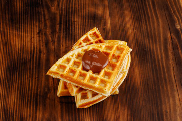 Waffles with honey, jam, and berries on wooden background
