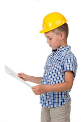 Thoughtful little builder boy in yellow hardhat and checkered shirt holding a paper plan in his hands, isolated on white