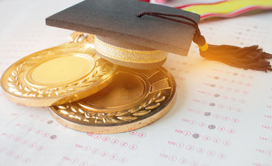 Blurred of graduation black cap on medals award winning and exams paper in test classroom, Concept...