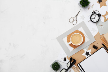 Fashion blogger workspace background. Coffee, office supply, alarm and clean notebook on white desk top view. Flat lay style. Copy space for text.