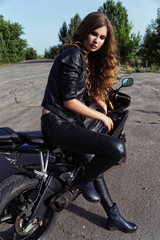 Fototapeta na wymiar young woman in leather clothes near a motorcycle