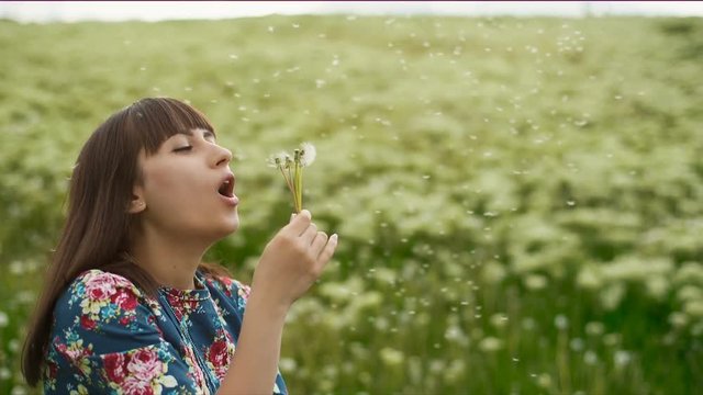 Smiling Woman Blowing on a Dandelion