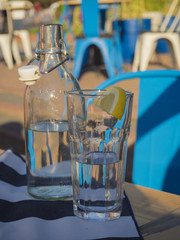 water glass bottle and glass with lemnon slice on restaurant table still life