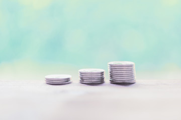 Silver coins on  wooden table with pastel blurred background,saving money concept
