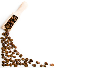 Coffee beans with wooden shovel scattered on a white