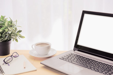 Minimal workspace,computer laptop,coffee cup,green  flowerpot,eyeglasses and notebook on wooden table over curtain white background